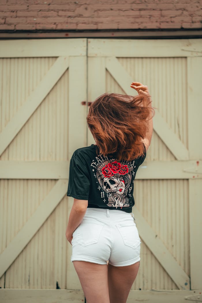HOME Woman with back turned, wearing shorts and printed t-shirt in urban background.