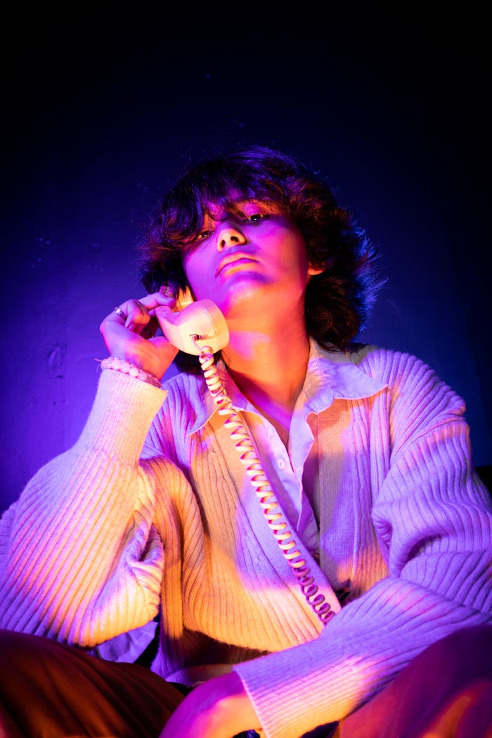 About Moody portrait of a person using a vintage phone in vibrant neon light.