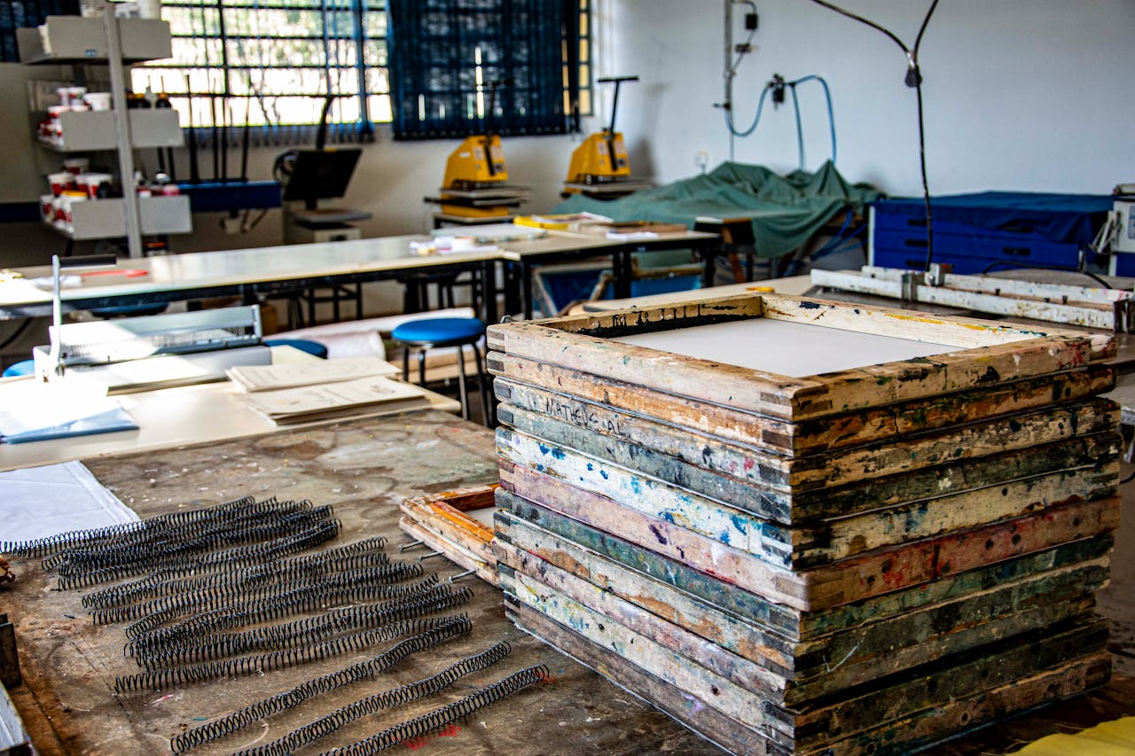 How It Works Interior of a textile workshop in Apucarana, highlighting screen printing frames and equipment.